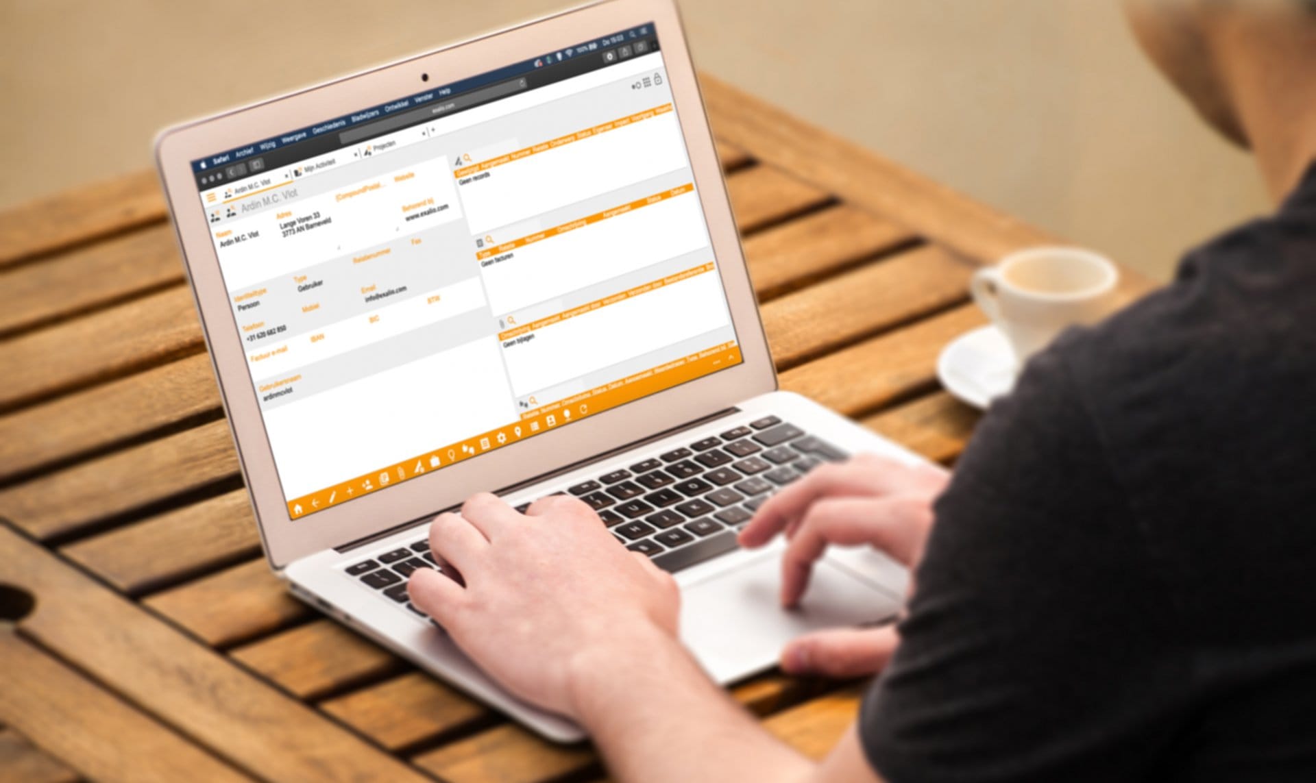 Man werkt in Exalio Business Solution op een laptop aan een houten tafel