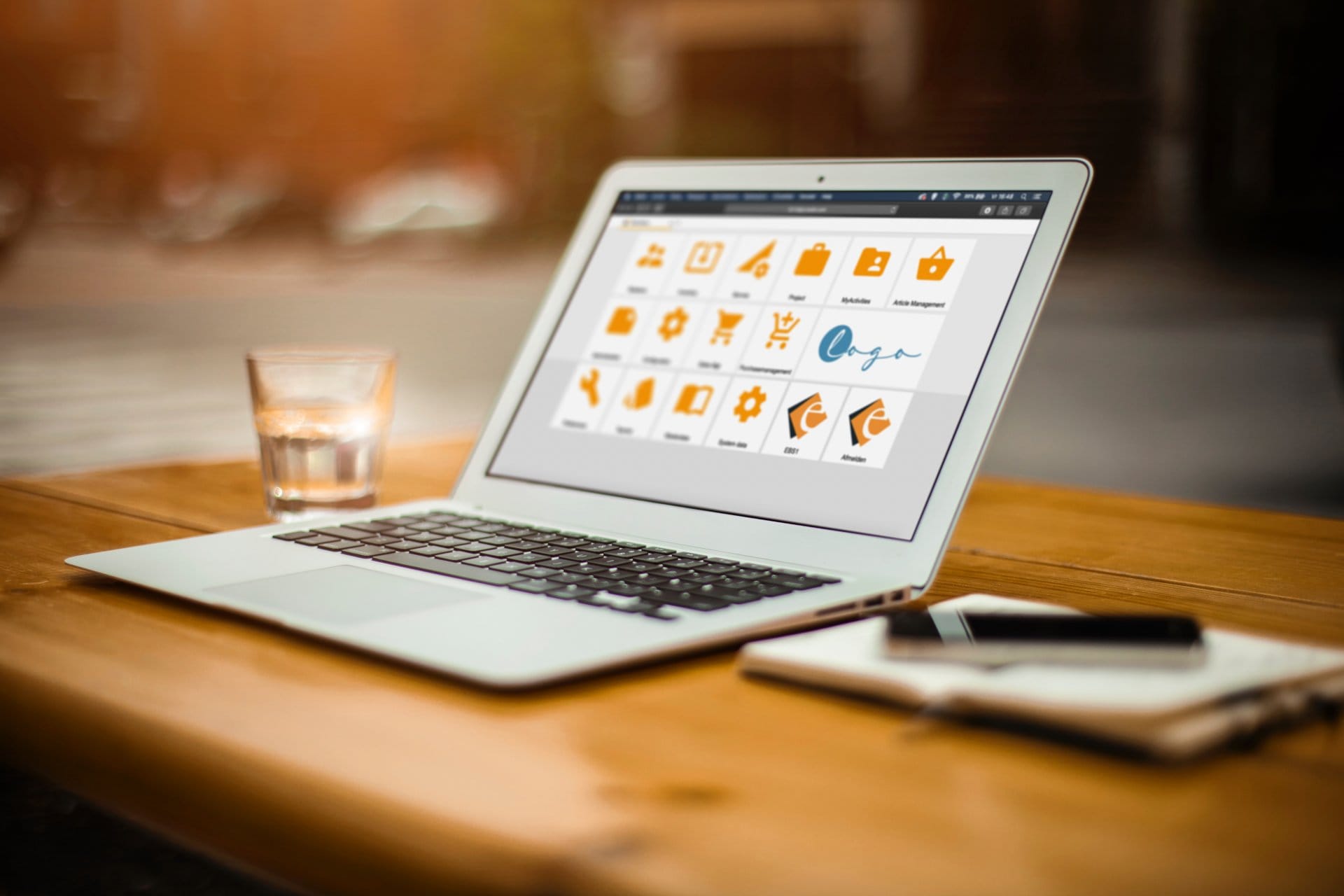 Laptop met Exalio Business Solution geopend op een houten bureau, naast een glas water en een smartphone